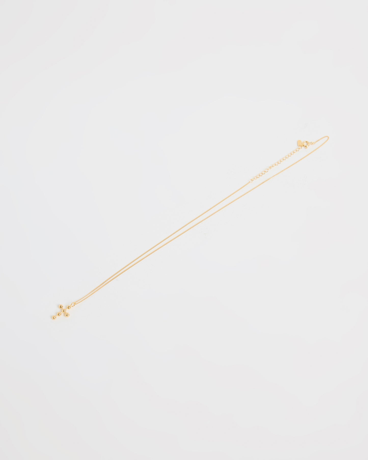 Full gold cross necklace with beaded pendant, laid flat on white background
