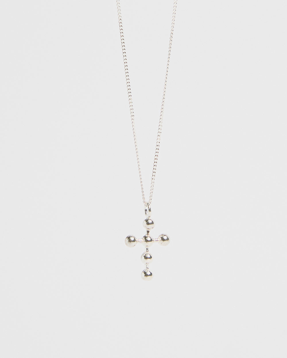 Silver cross pendant with orb accents, hanging from fine chain, isolated on white
