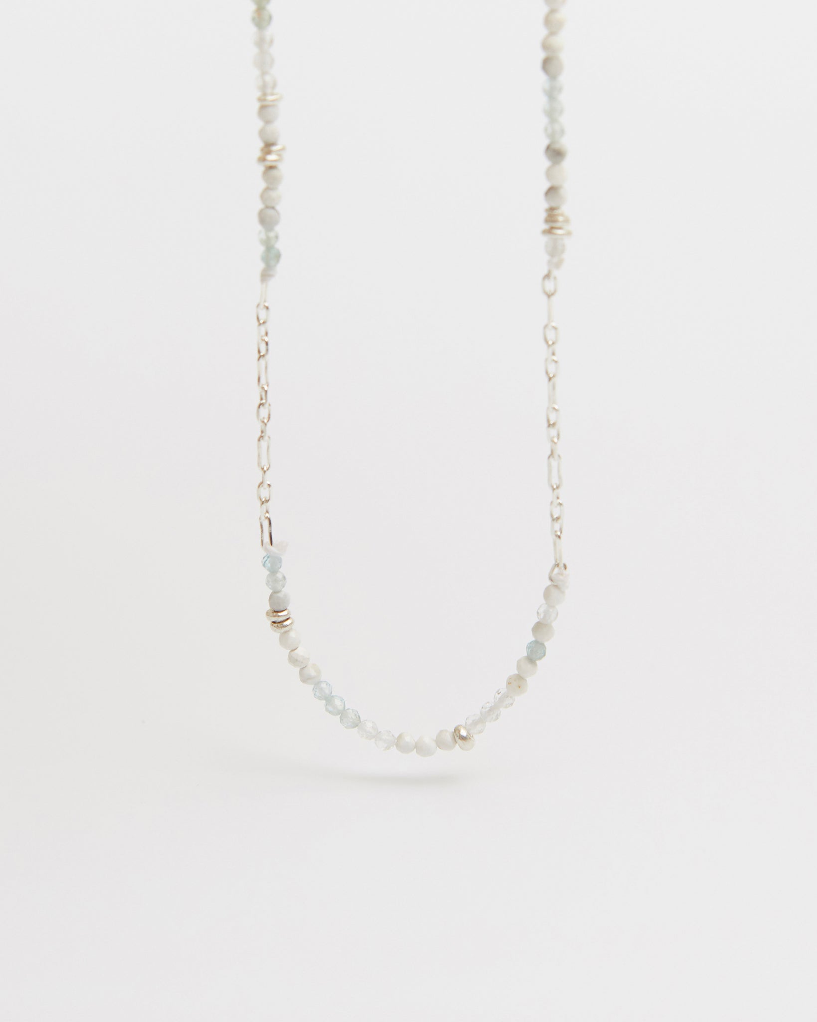 floating product shot of beaded and silver chain necklace centered against white