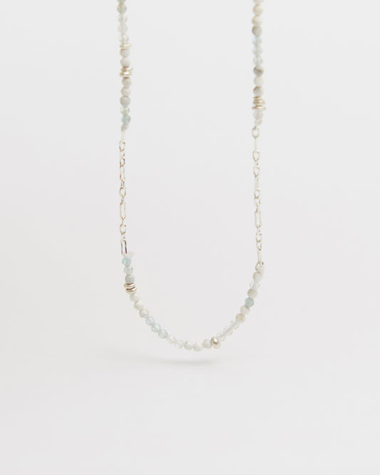 floating product shot of beaded and silver chain necklace centered against white
