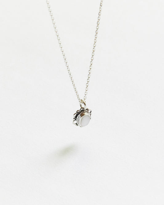 white oval stone necklace with detailed silver frame, photographed on white background