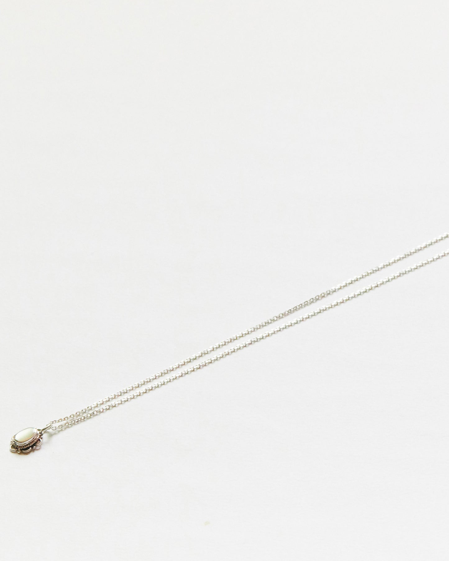  Small black oval stone necklace suspended mid-air on white background