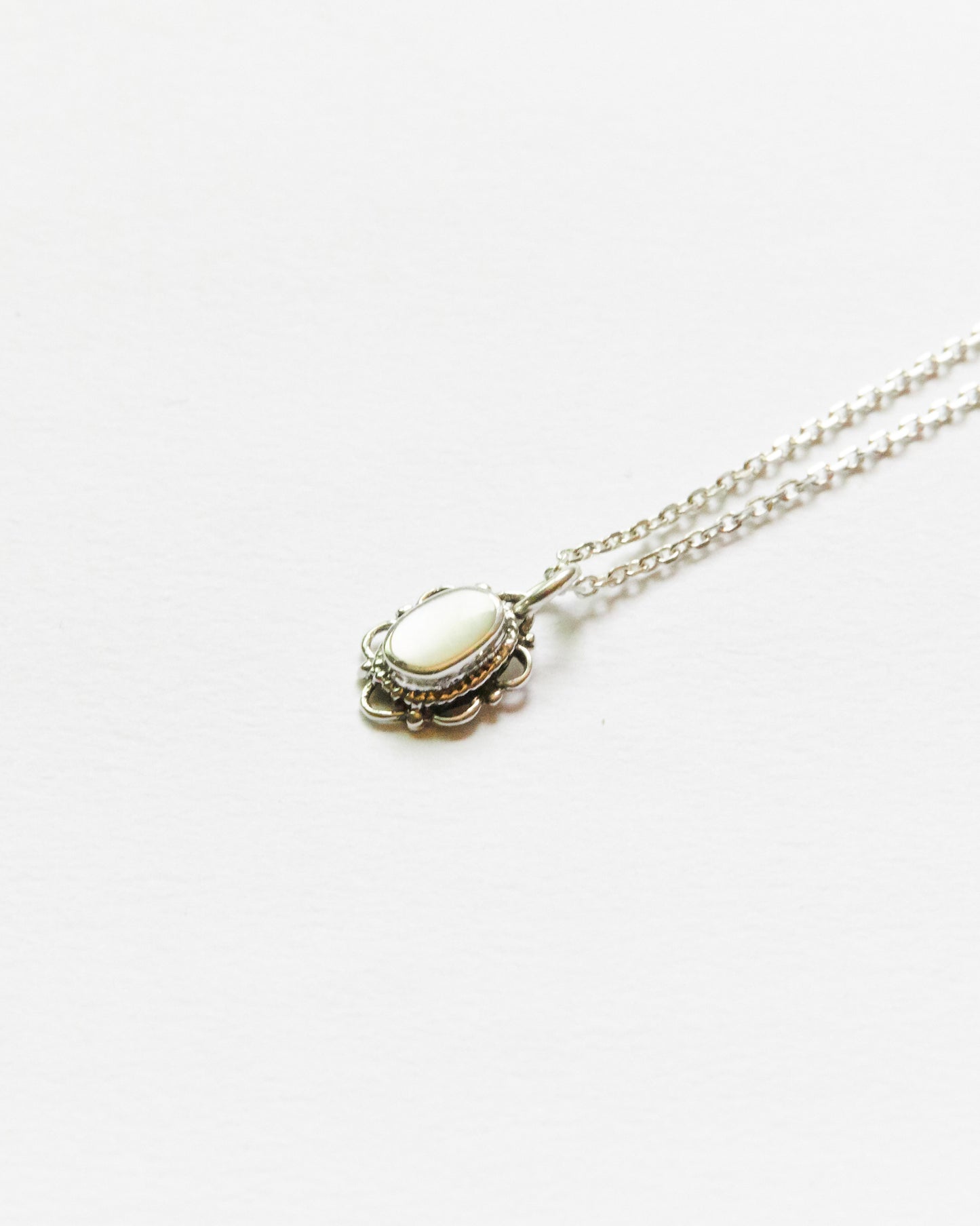 Silver chain necklace with black oval pendant shown diagonally across a white surface