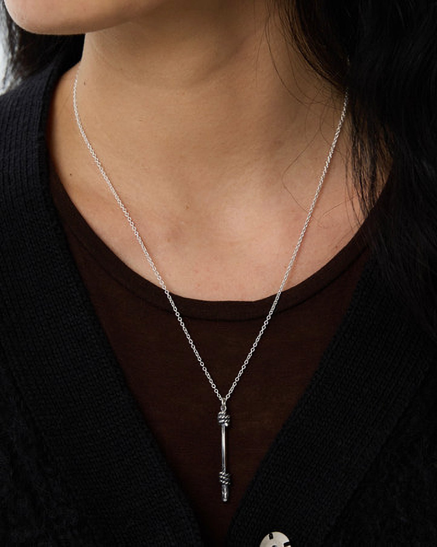Silver necklace with a pendant worn by a person against a dark background