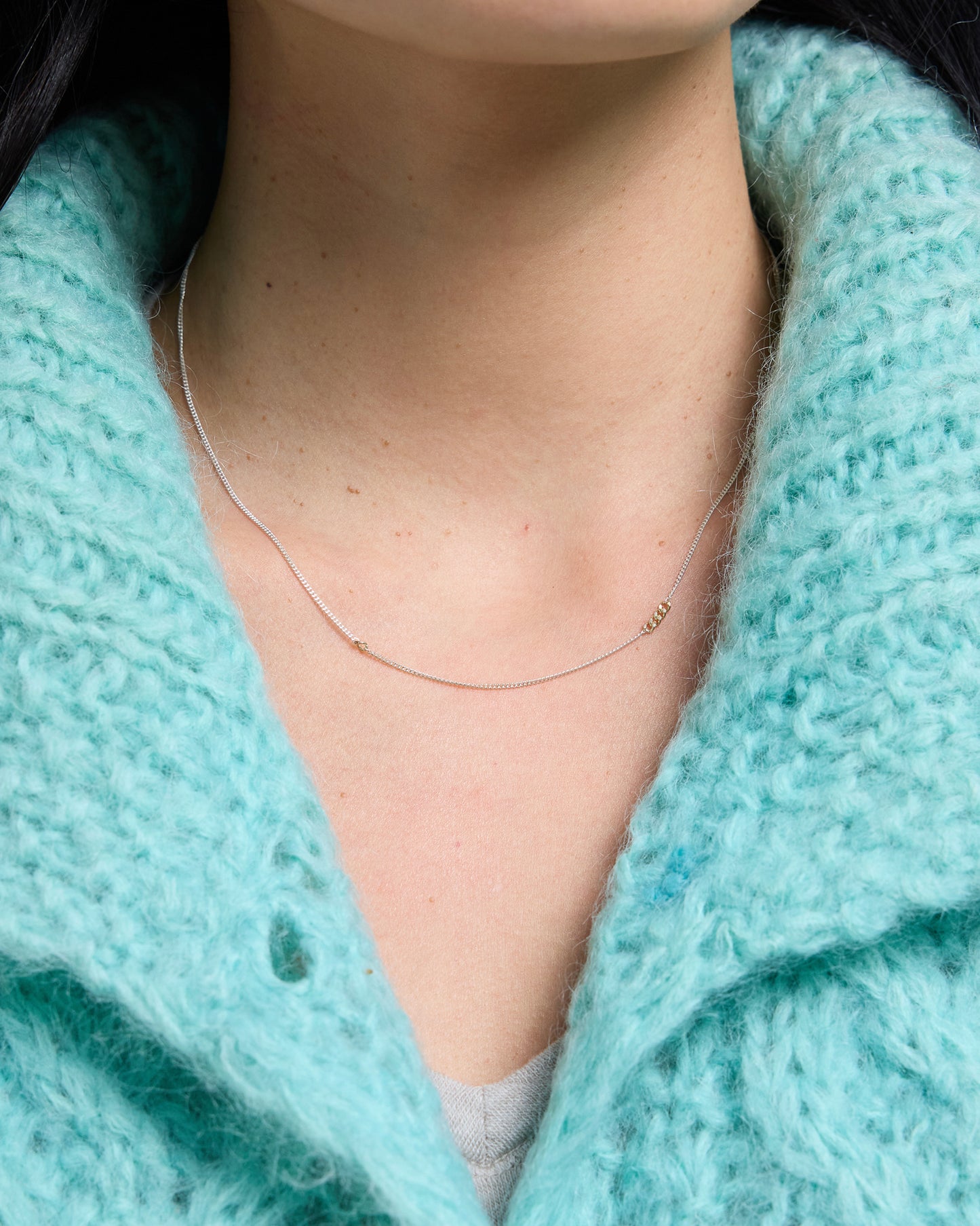 Woman wearing a delicate sterling silver chain necklace with gold link accents