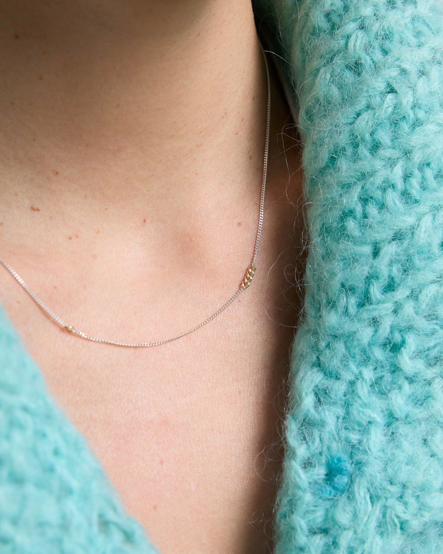 Close-up view of mixed metal chain necklace featuring small gold links on silver chain