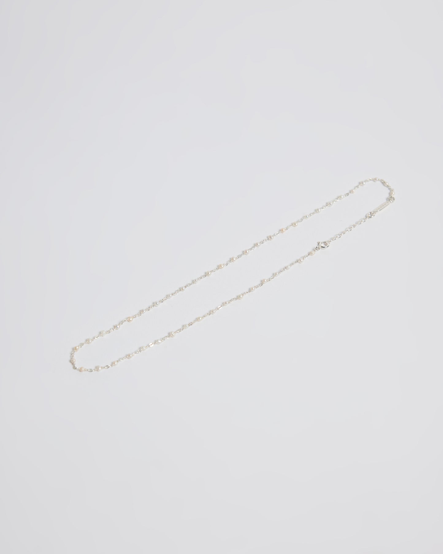 laid flat showing the fine silver chain with tiny pearl accents