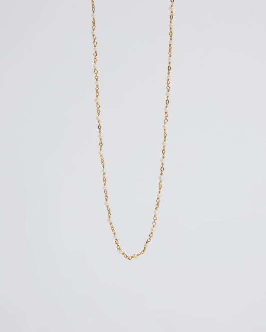 a long delicate pearl necklace draped naturally over the hand