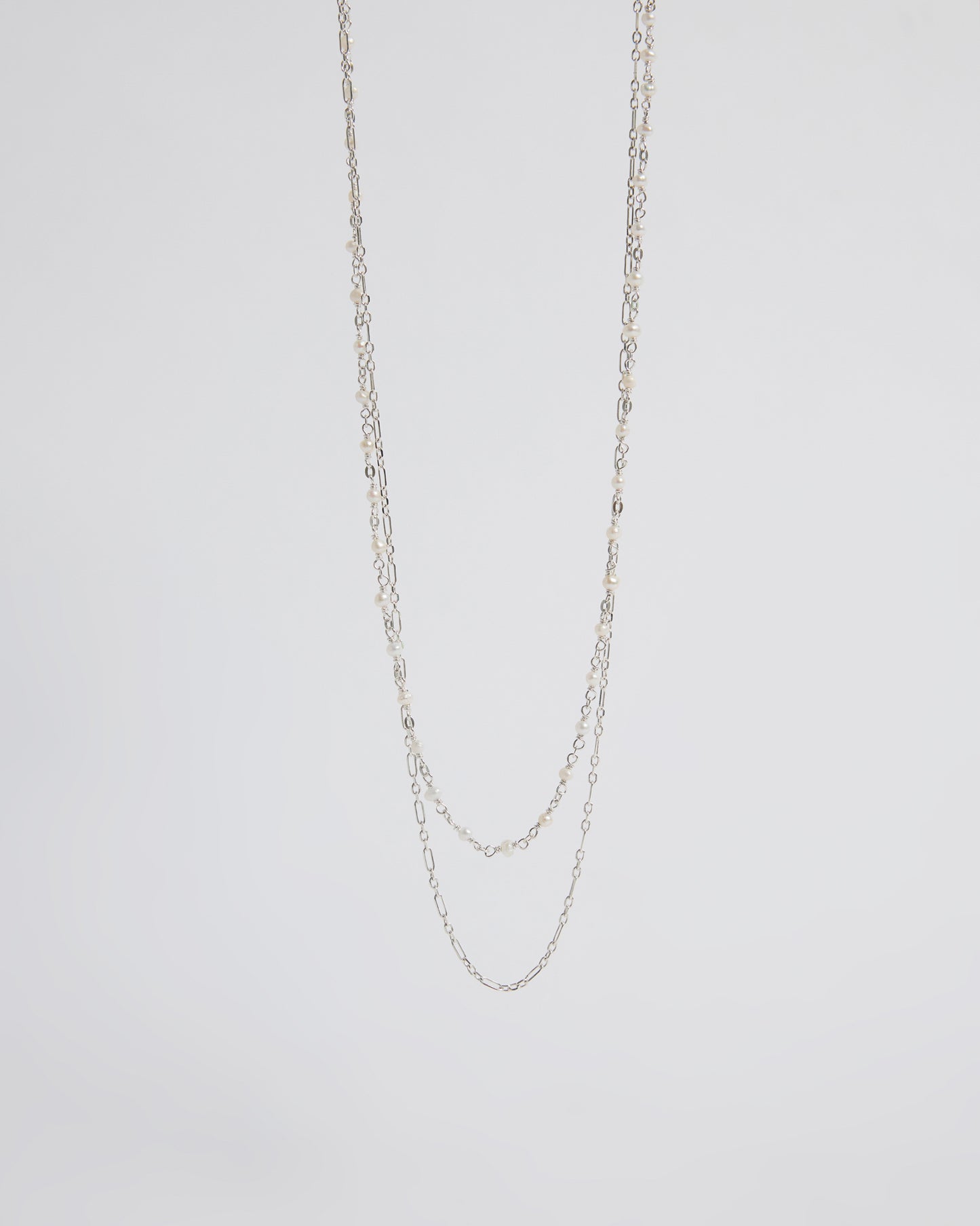 Silver chain necklace on a light gray background