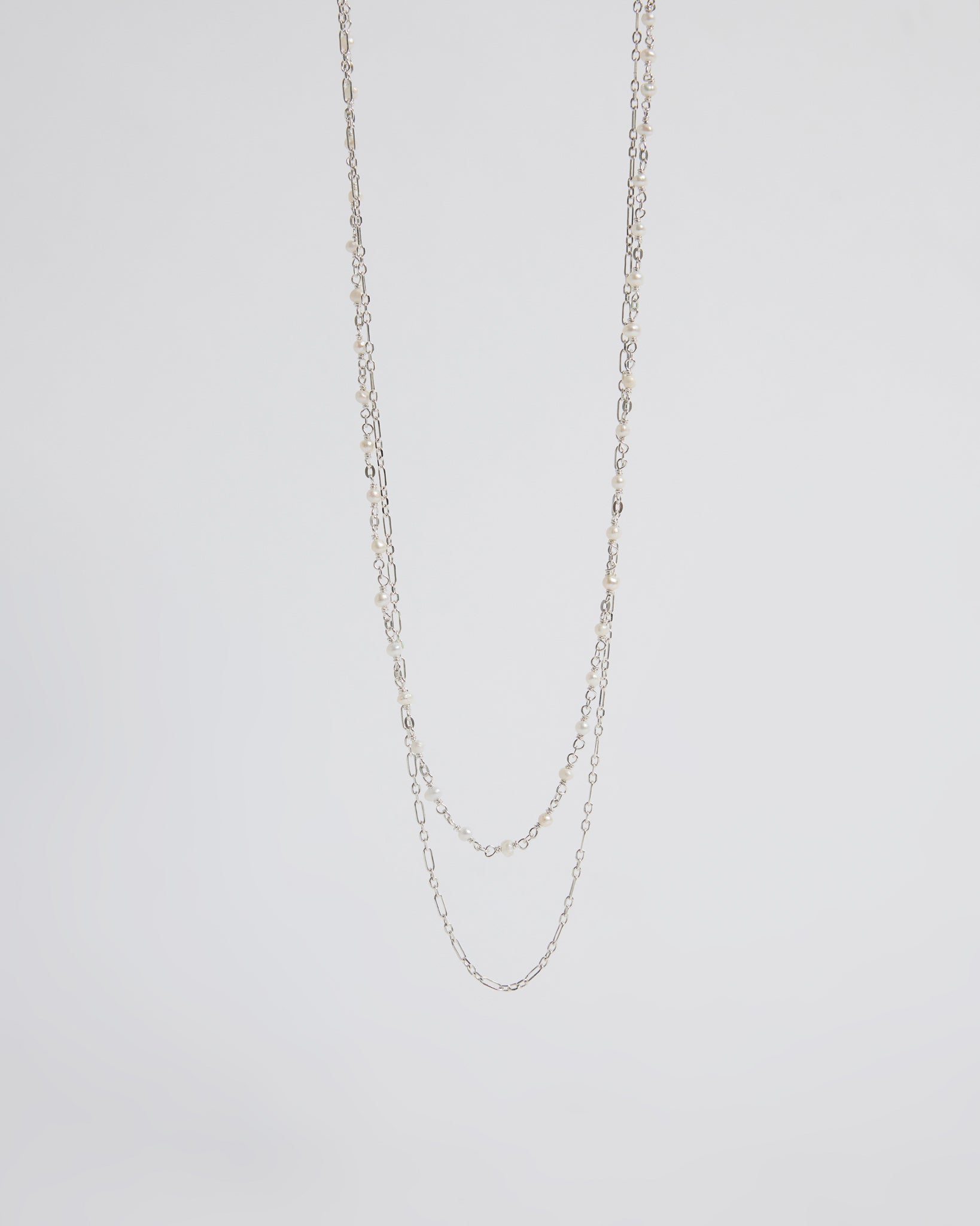 Silver chain necklace on a light gray background