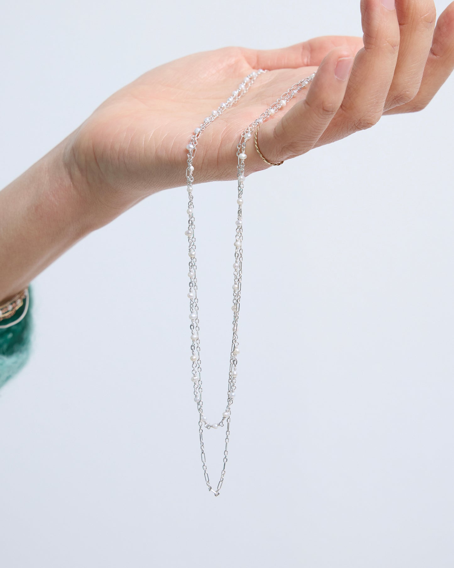 side view of a layered pearl and gold chain necklace sitting naturally along the neckline