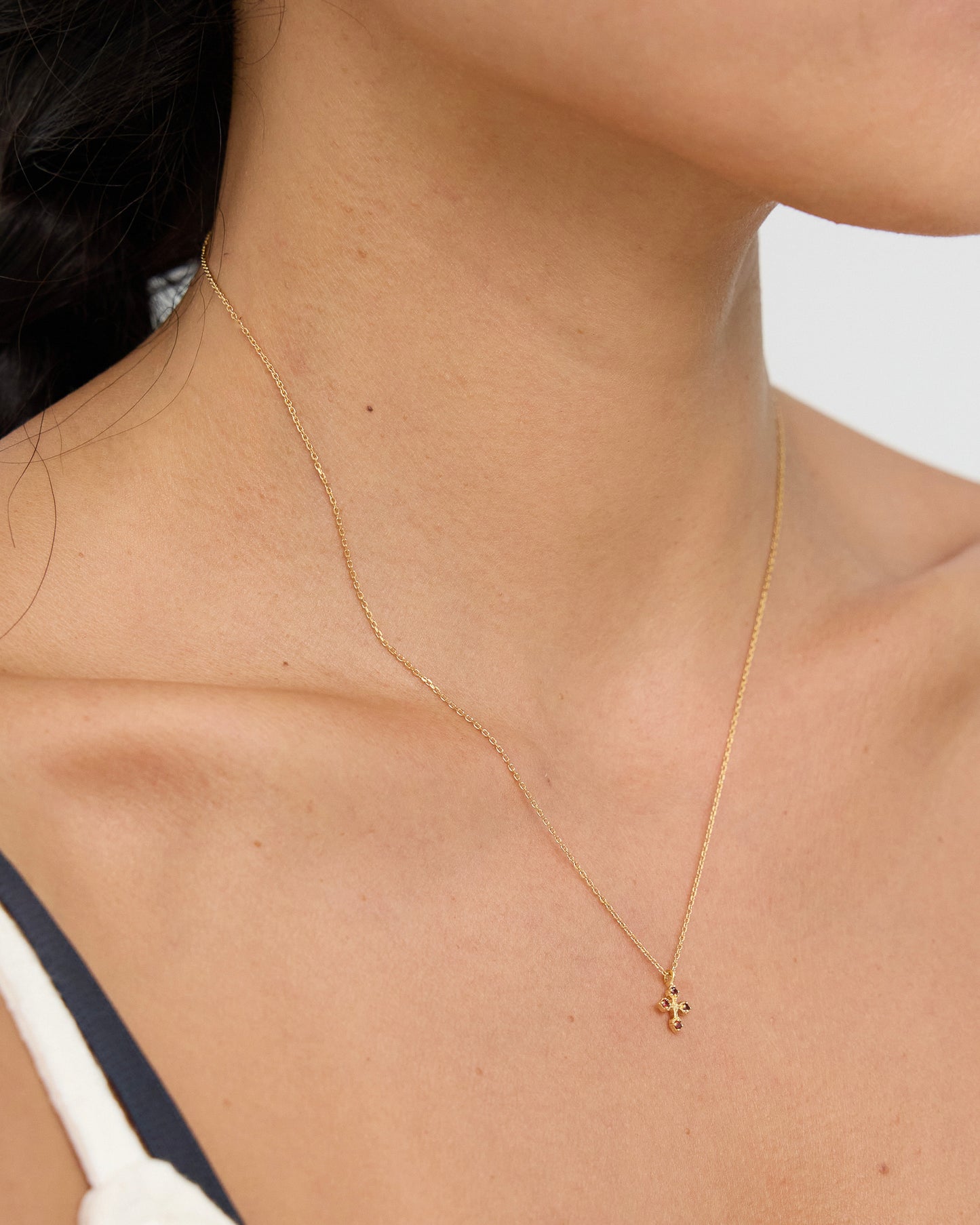 Close-up of a person wearing a delicate gold necklace with a small pendant.