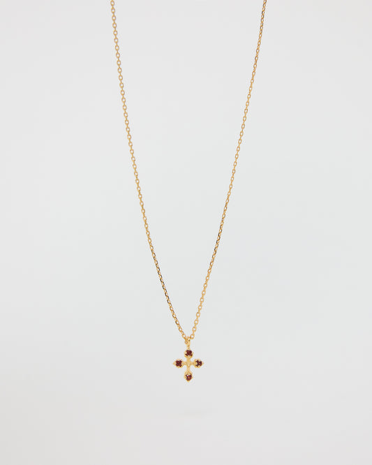 Gold necklace with a small cross pendant on a light gray background