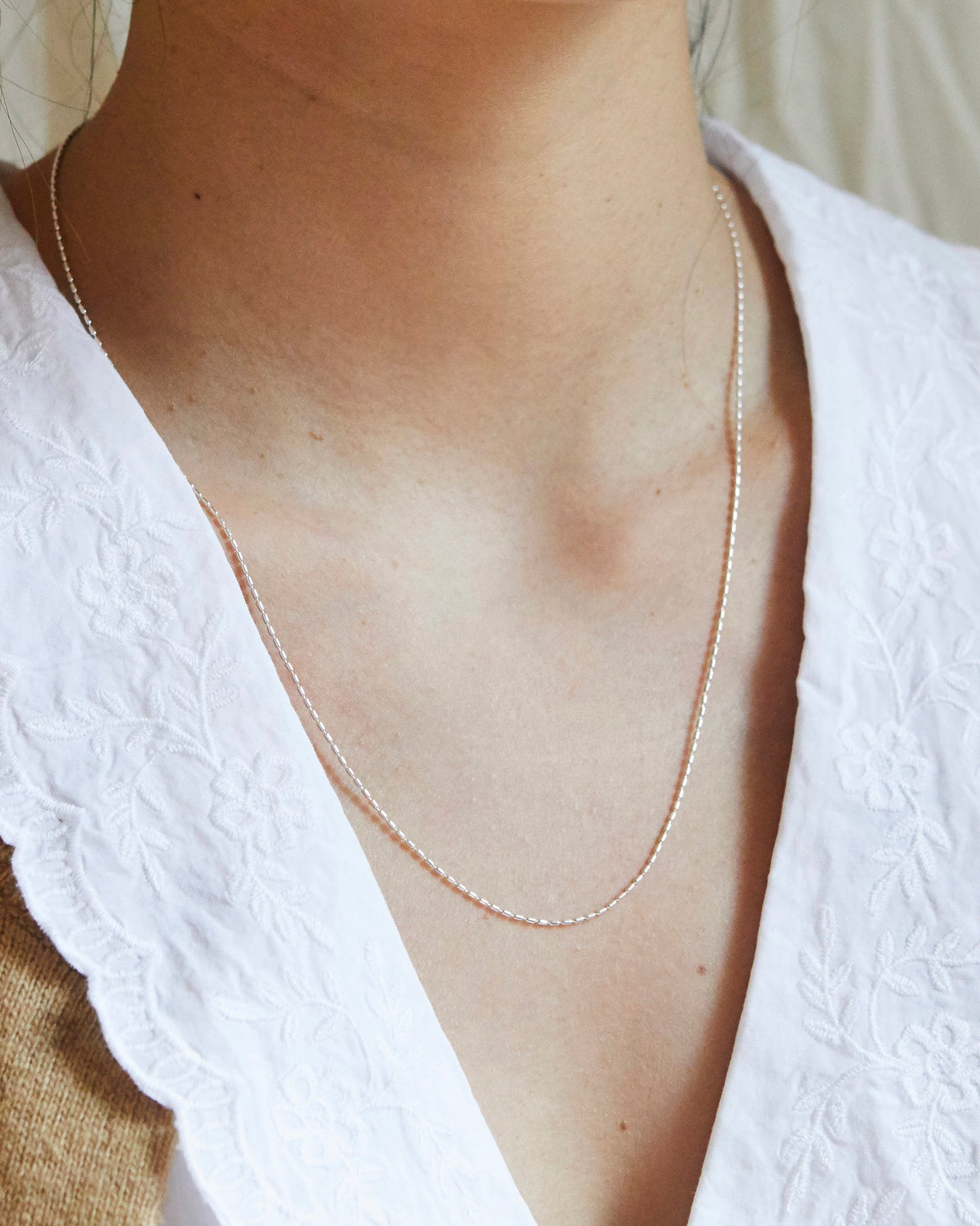 a barely-there sterling silver chain catching light like it knows it’s the main character in your everyday layering look