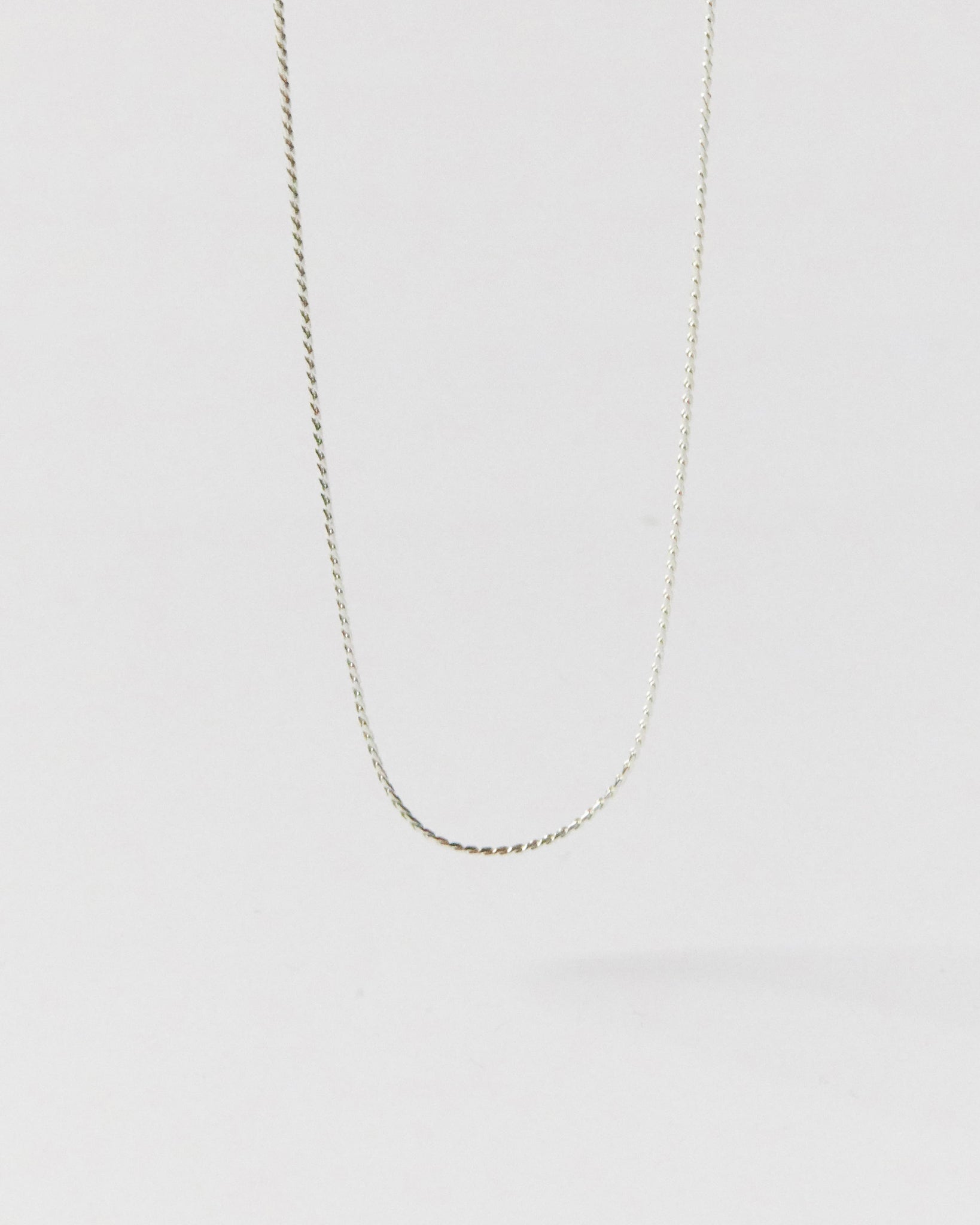 Silver chain necklace on a light gray background