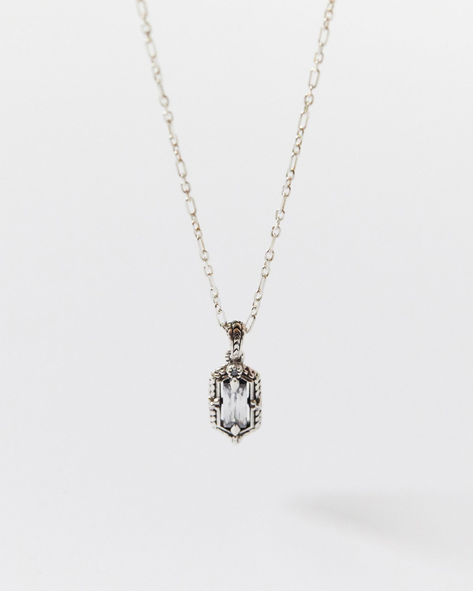 Silver necklace with a rectangular pendant on a white background