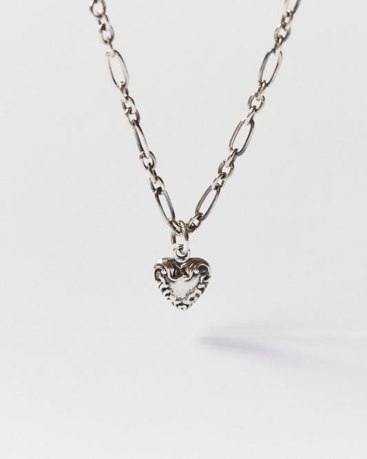 Close-up of a silver heart pendant necklace with mixed chain on skin
