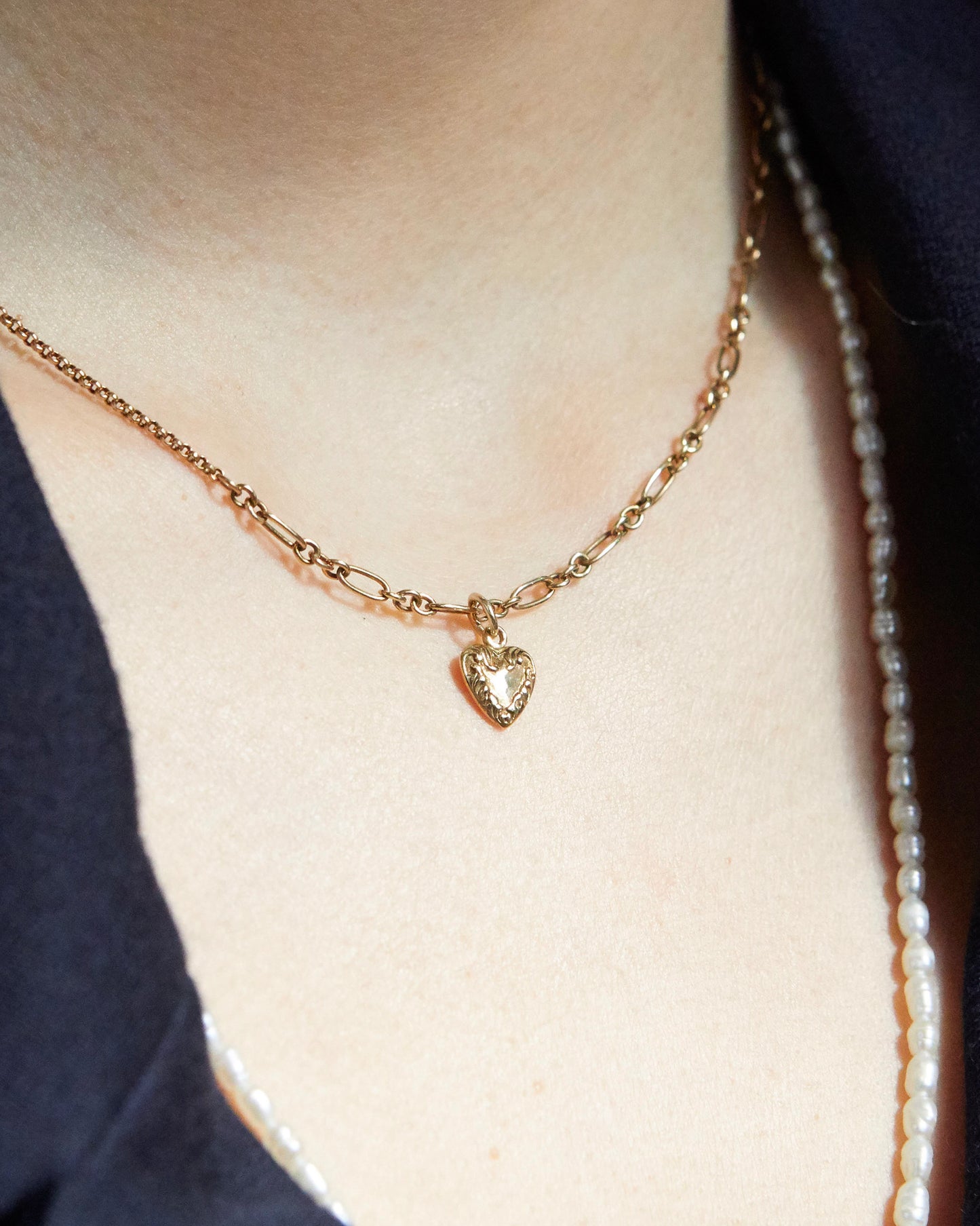 Macro shot of antique-style gold heart pendant and textured chain
