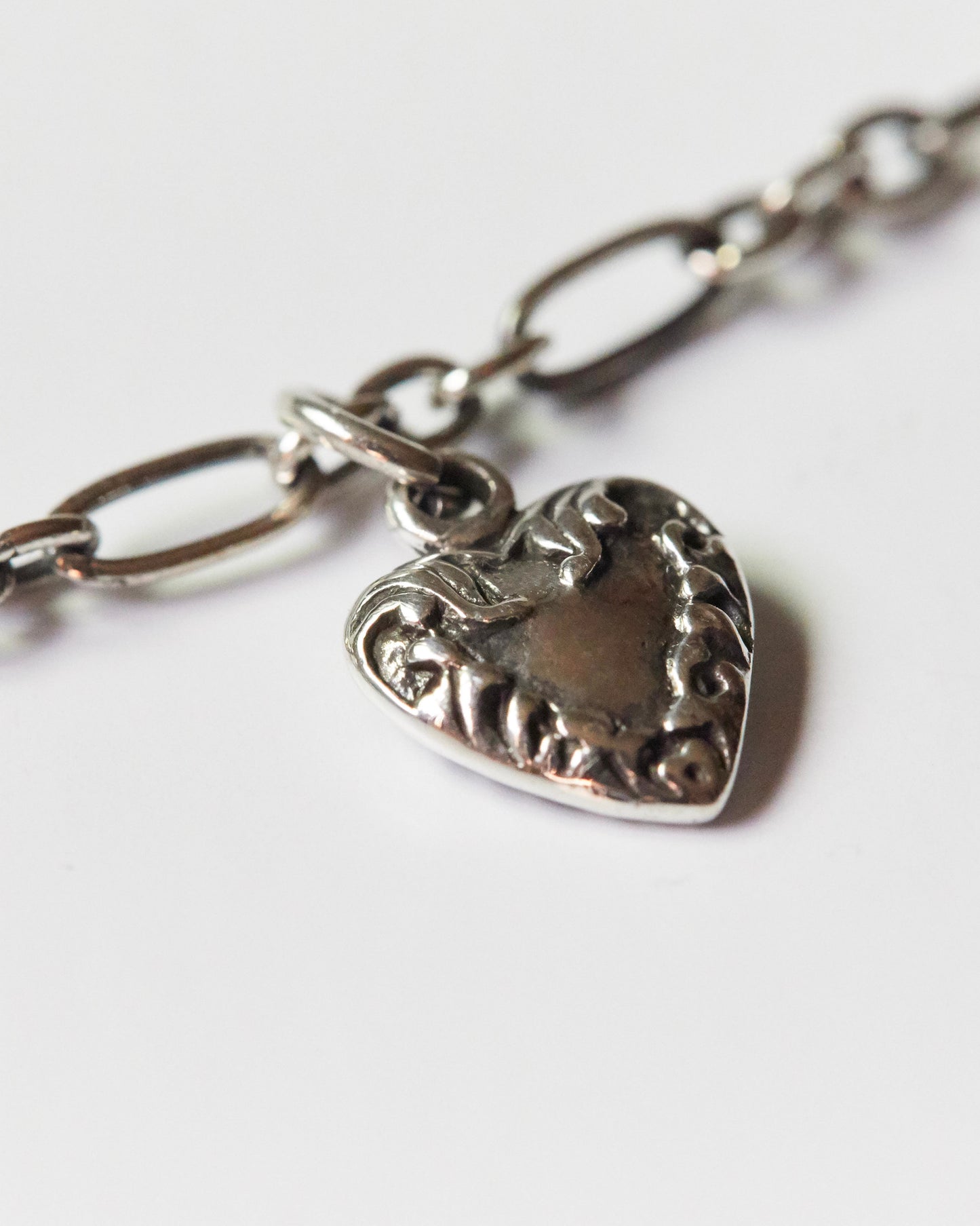 Soft silver heart pendant necklace worn around neck with clean collar
