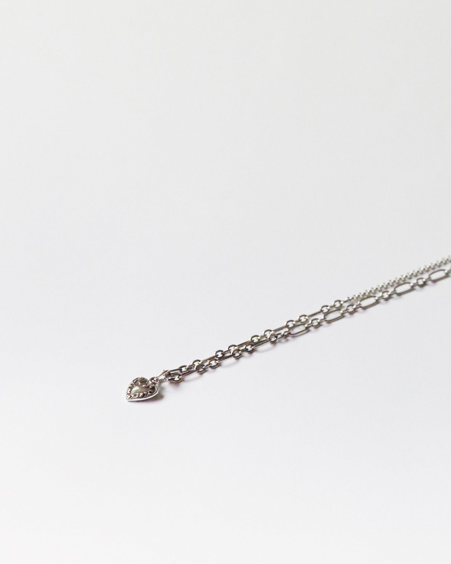 Flat lay of gold heart charm necklace against clean white background
