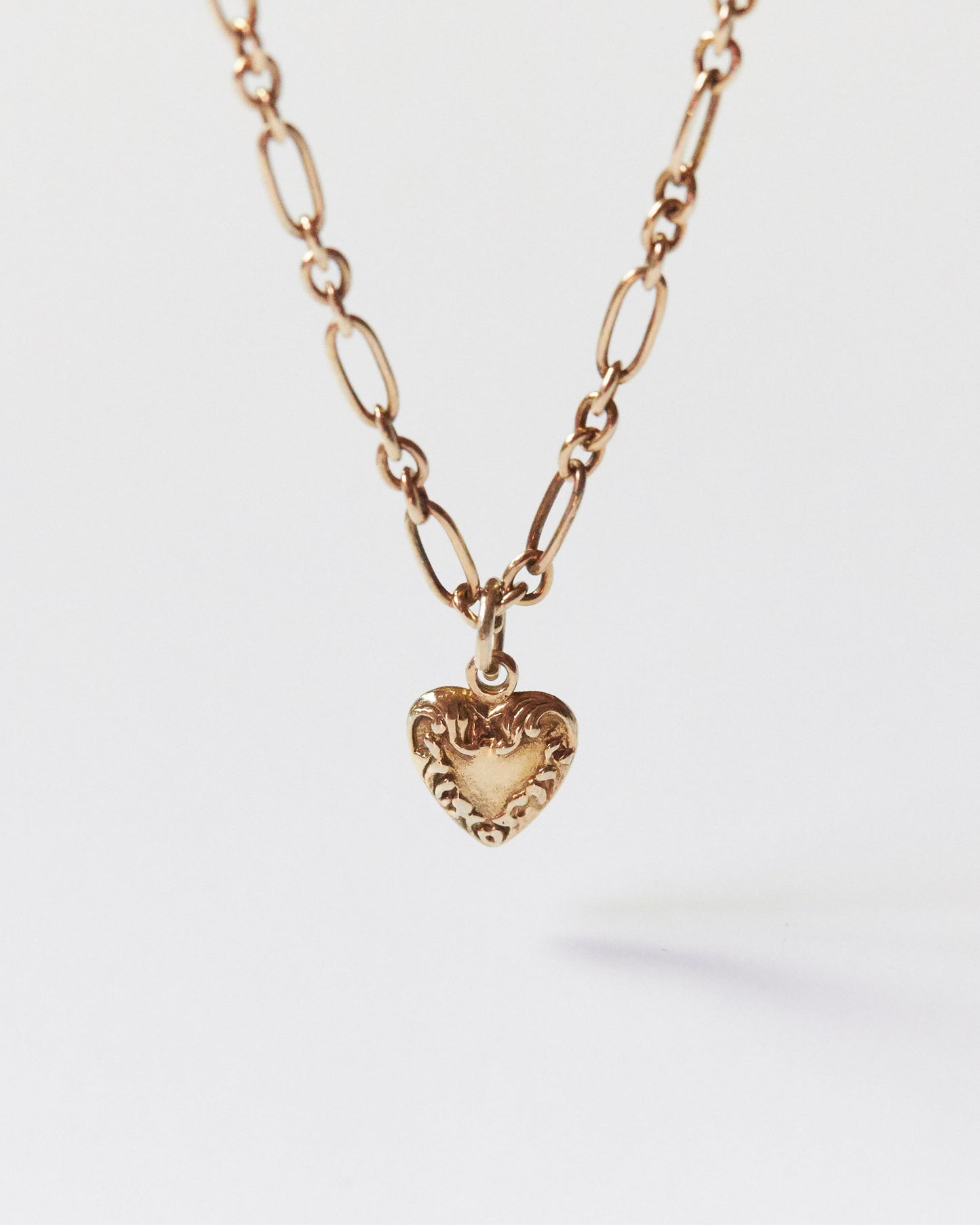 Macro close-up of gold heart pendant showing engraving texture
