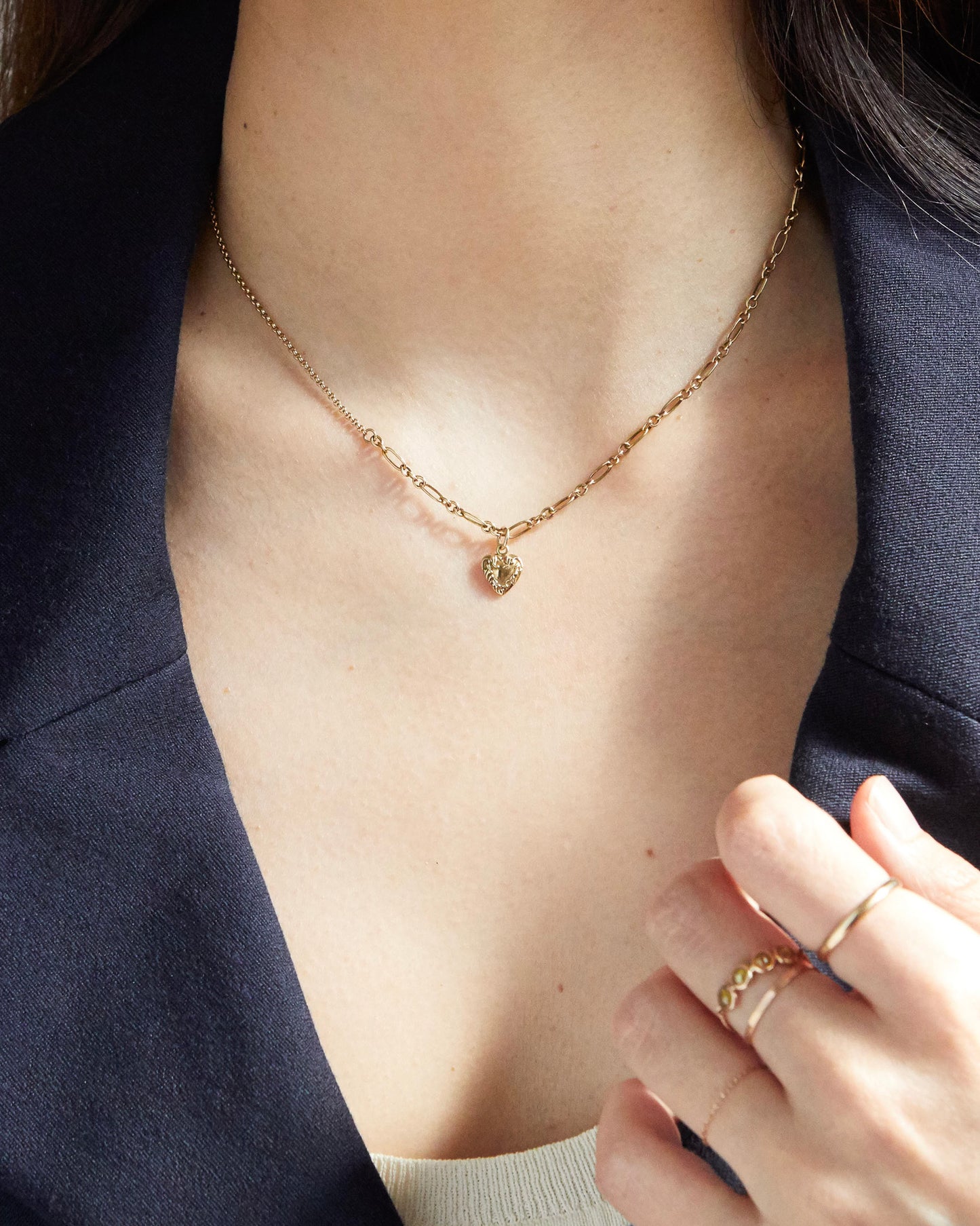 Centered shot of gold heart charm hanging from paperclip chain
