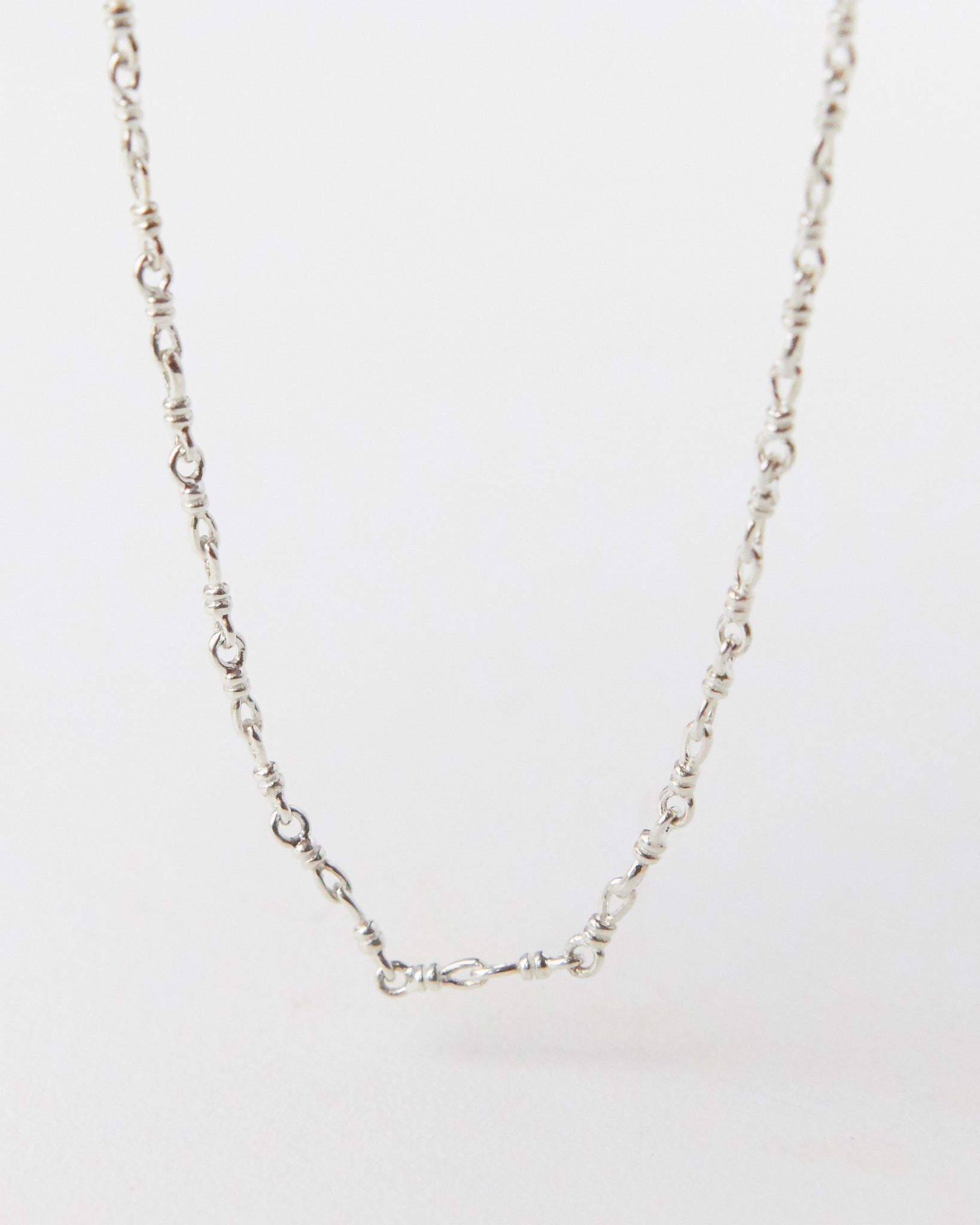 Silver chain necklace on a light gray background