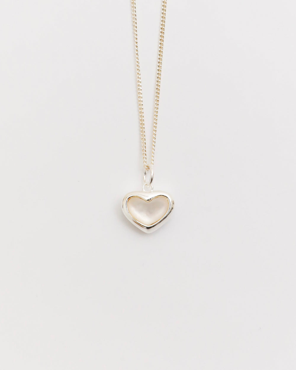 silver heart necklace with mother of pearl pendant on fine chain, minimal jewelry flat lay