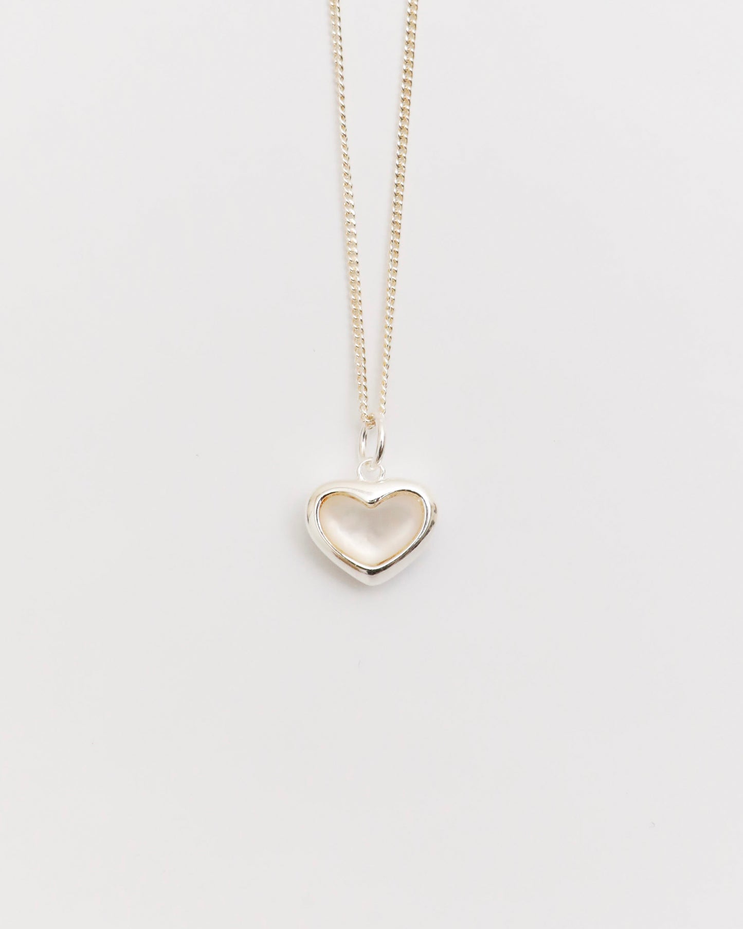 silver heart necklace with mother of pearl pendant on fine chain, minimal jewelry flat lay