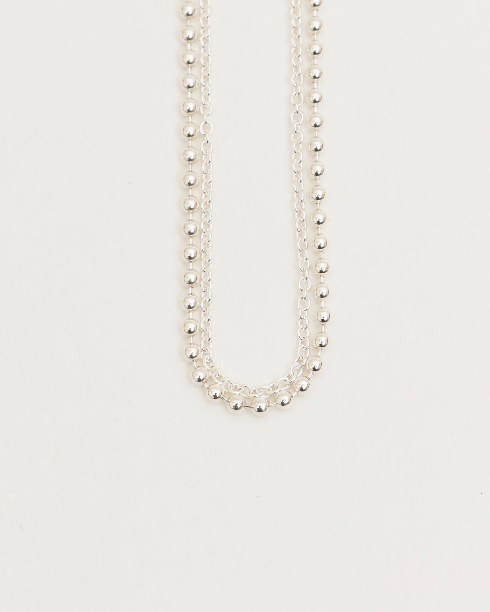 Silver beaded necklace on a light gray background