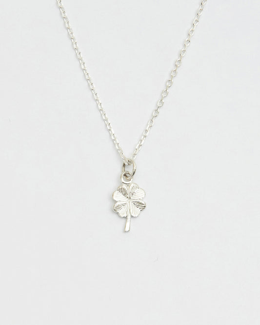 Minimal silver four leaf clover necklace displayed on white background