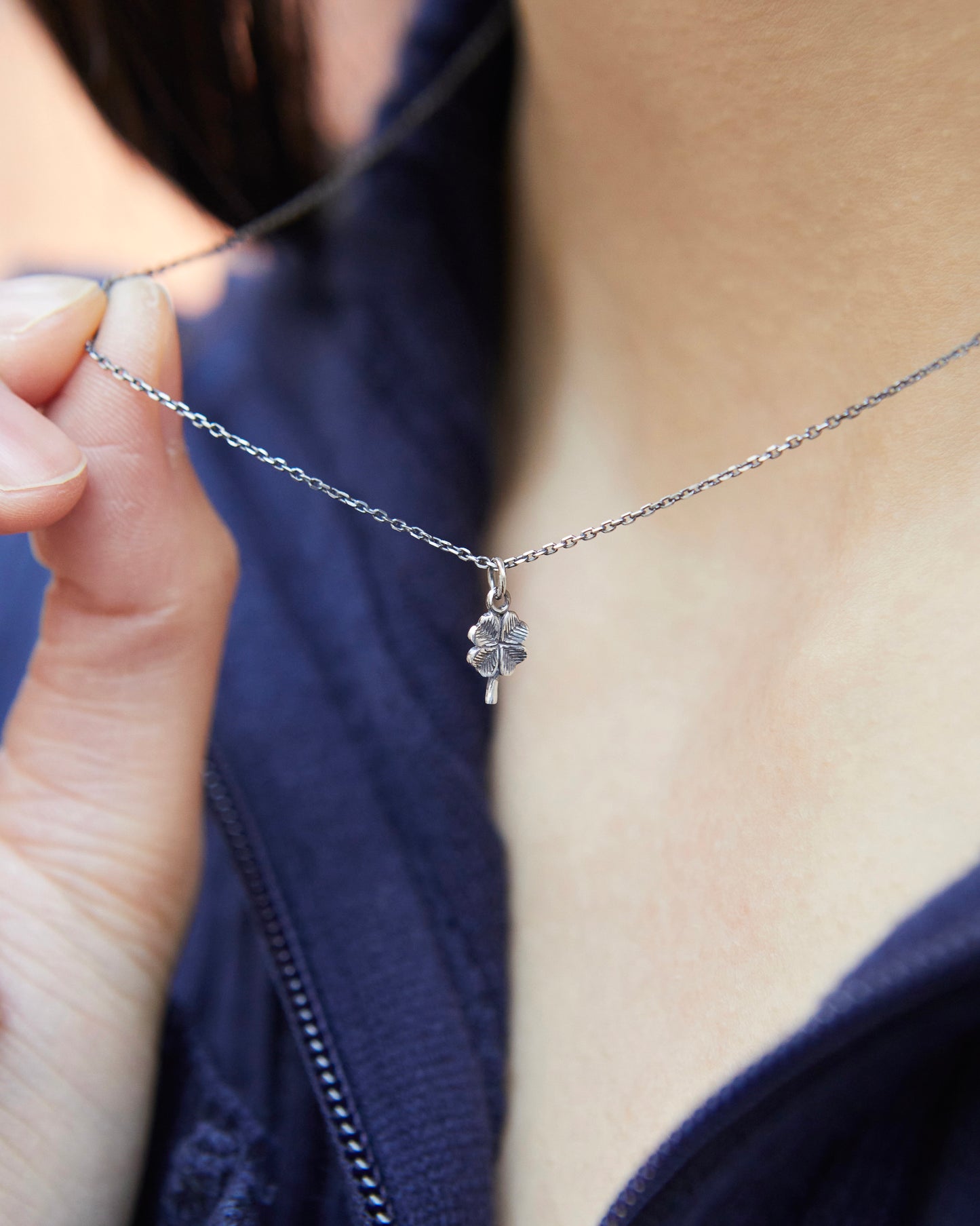 Close-up side angle of tiny silver four leaf clover pendant necklace