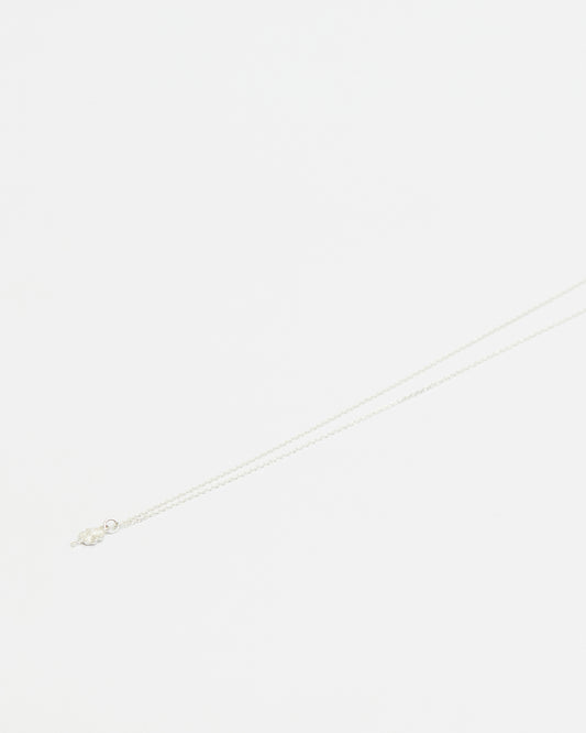 Close-up of delicate silver four leaf clover pendant necklace on white background