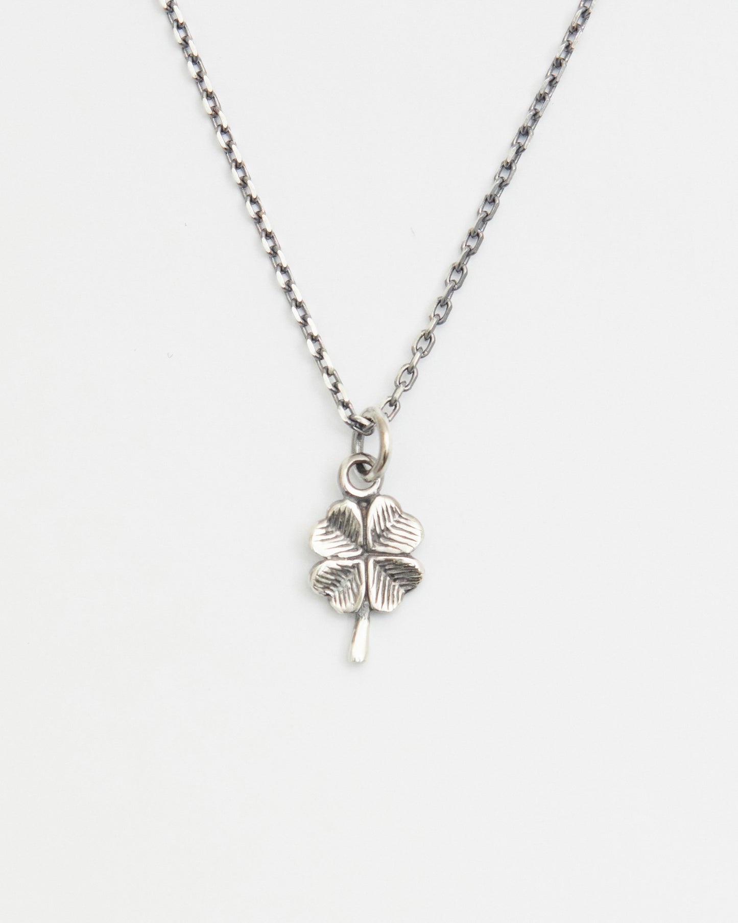 Minimal antique silver four leaf clover necklace displayed on white background