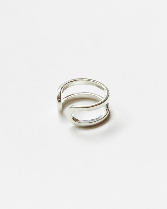 Close-up product image of a minimalist sterling silver open ring with double curved band design on clean white background, featuring sculptural contemporary silhouette.