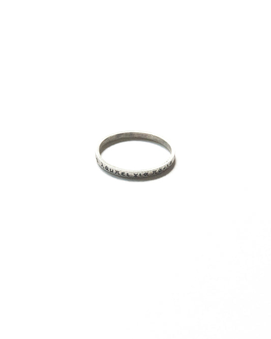 Close-up of a thin silver ring engraved with Greek text, photographed on a white background