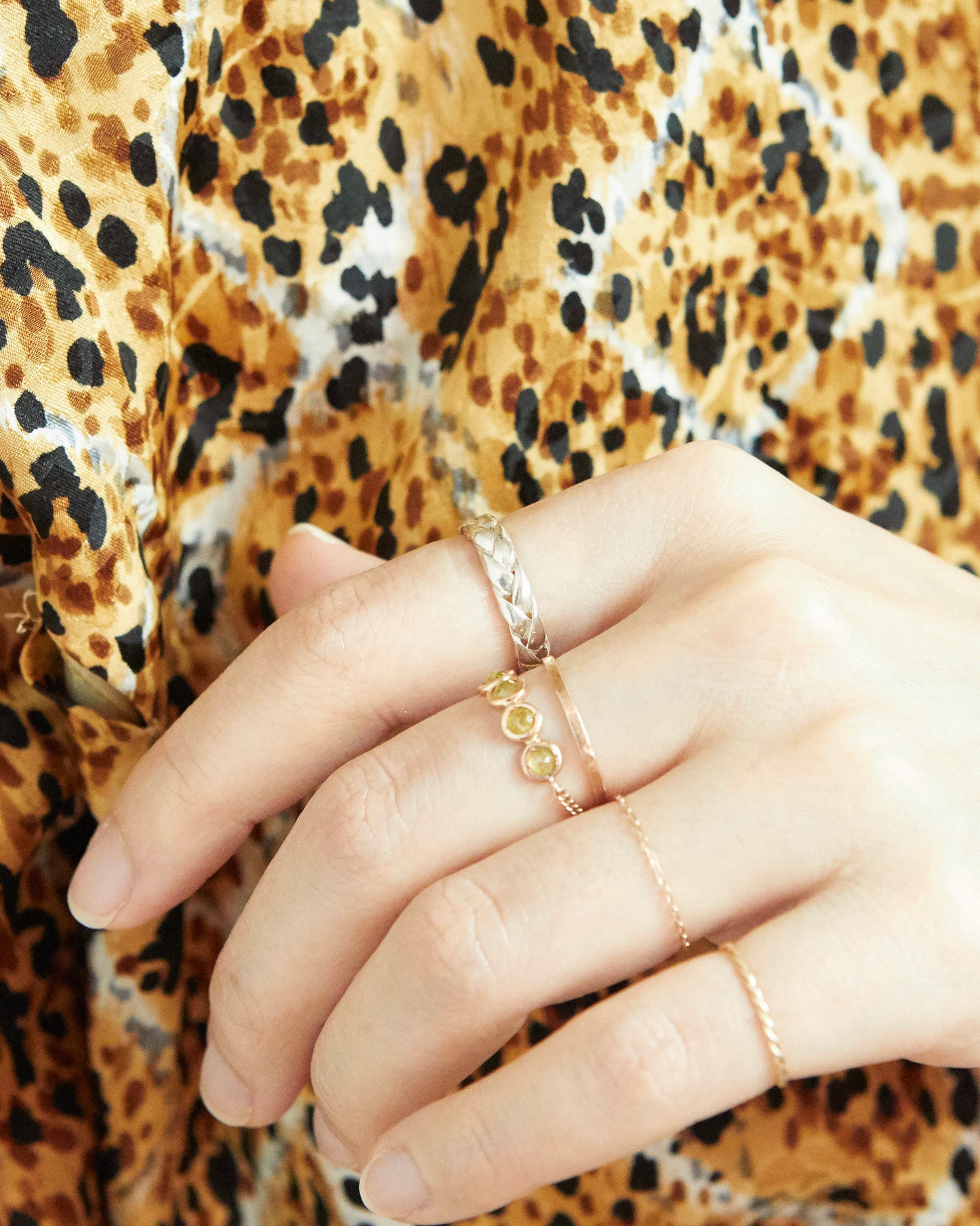 Close-up side view of the silver braided ring on white surface, emphasizing the dimensional pattern and smooth finish