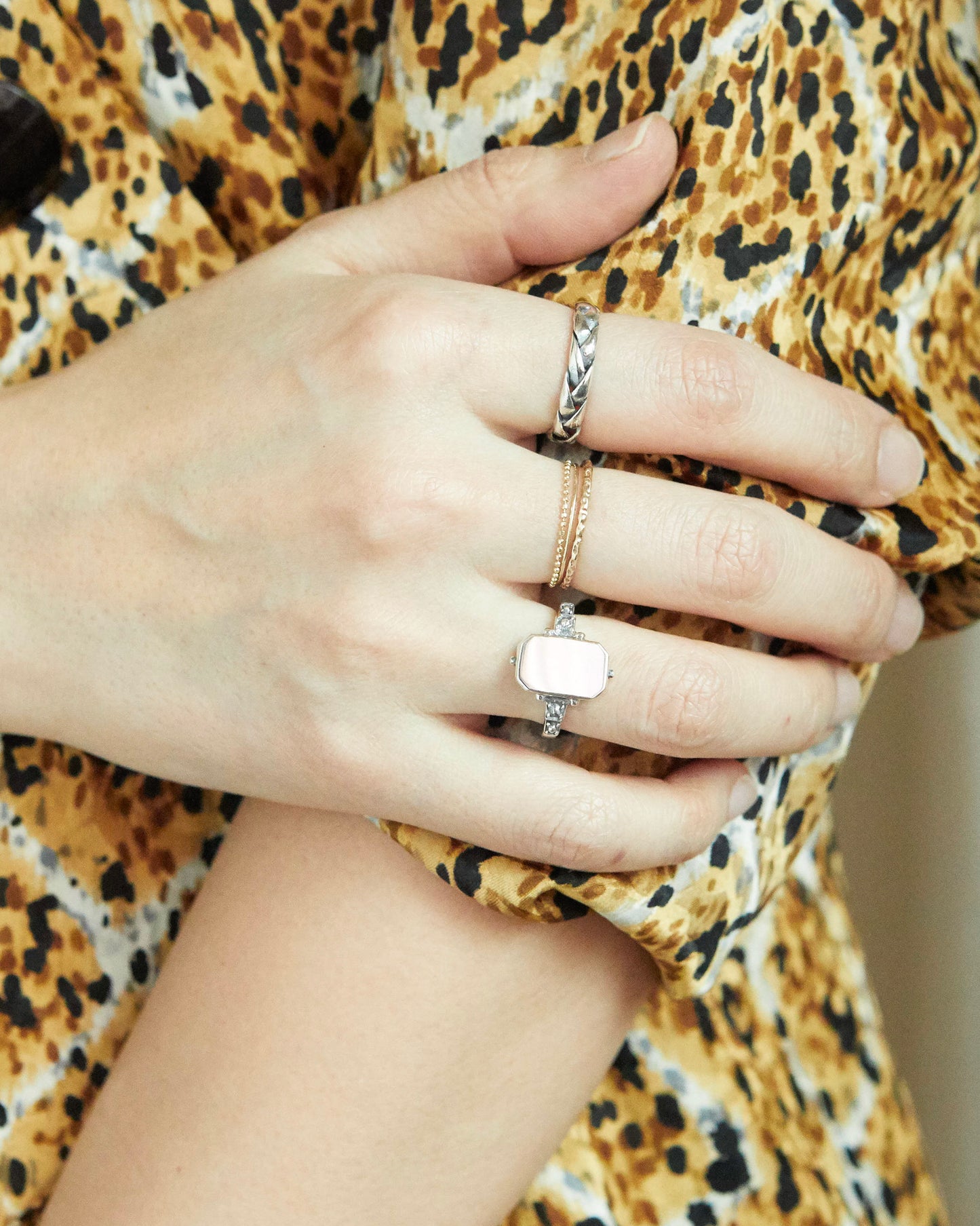 Hand wearing two rings with a leopard print garment in the background