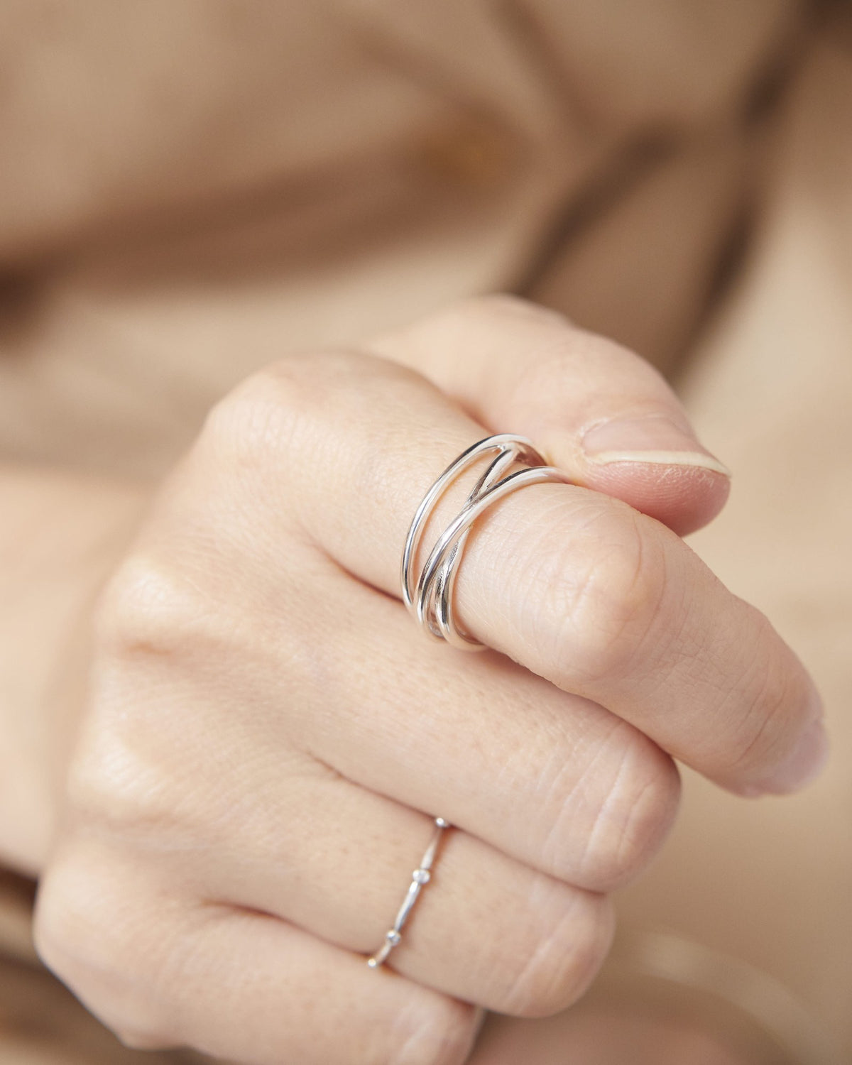 Close-up of a hand wearing a sterling silver crossover wire ring – HANNA543 R506 triple air lines