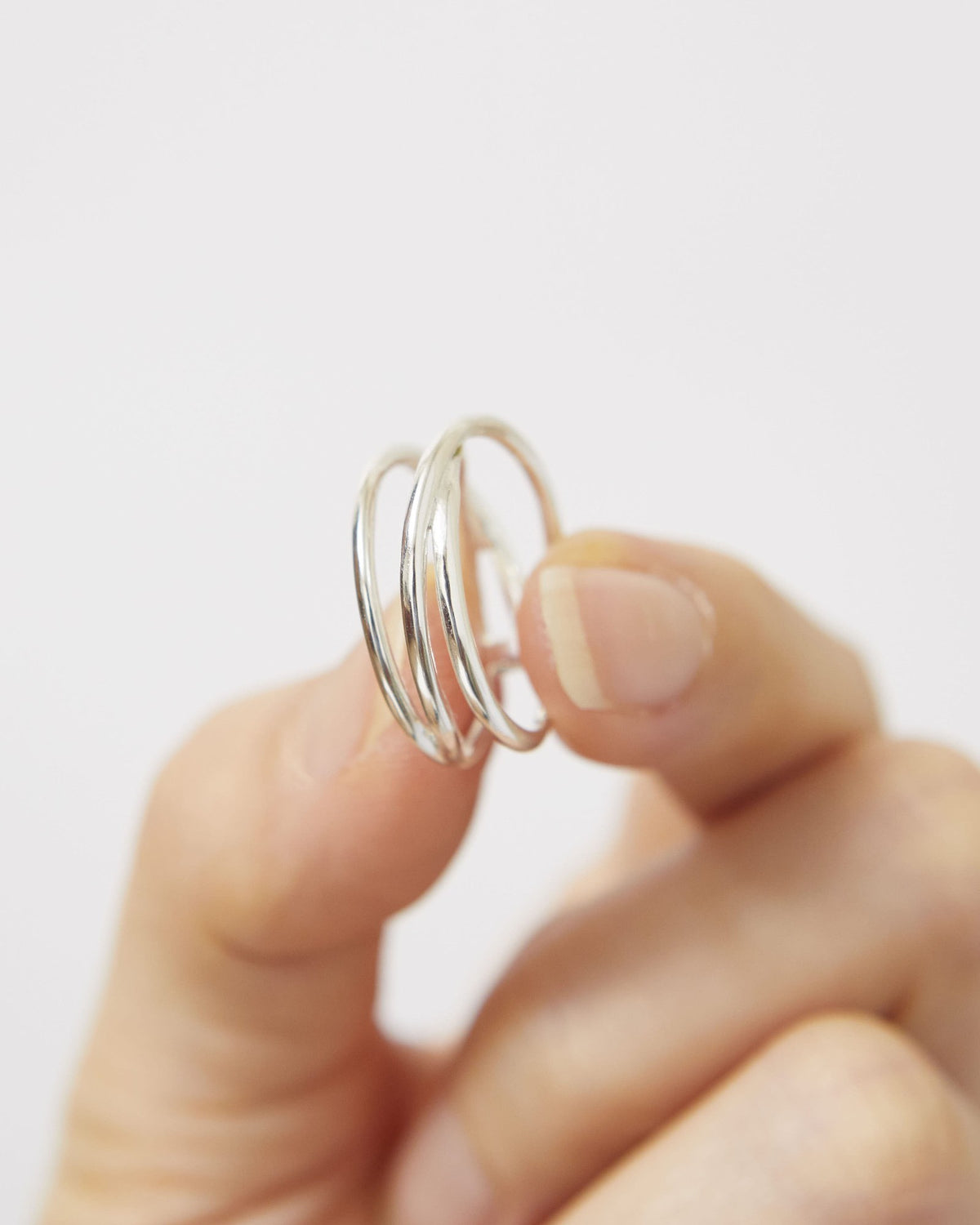 Fingers holding a sterling silver triple line ring to show its open form – HANNA543 R506 triple air lines