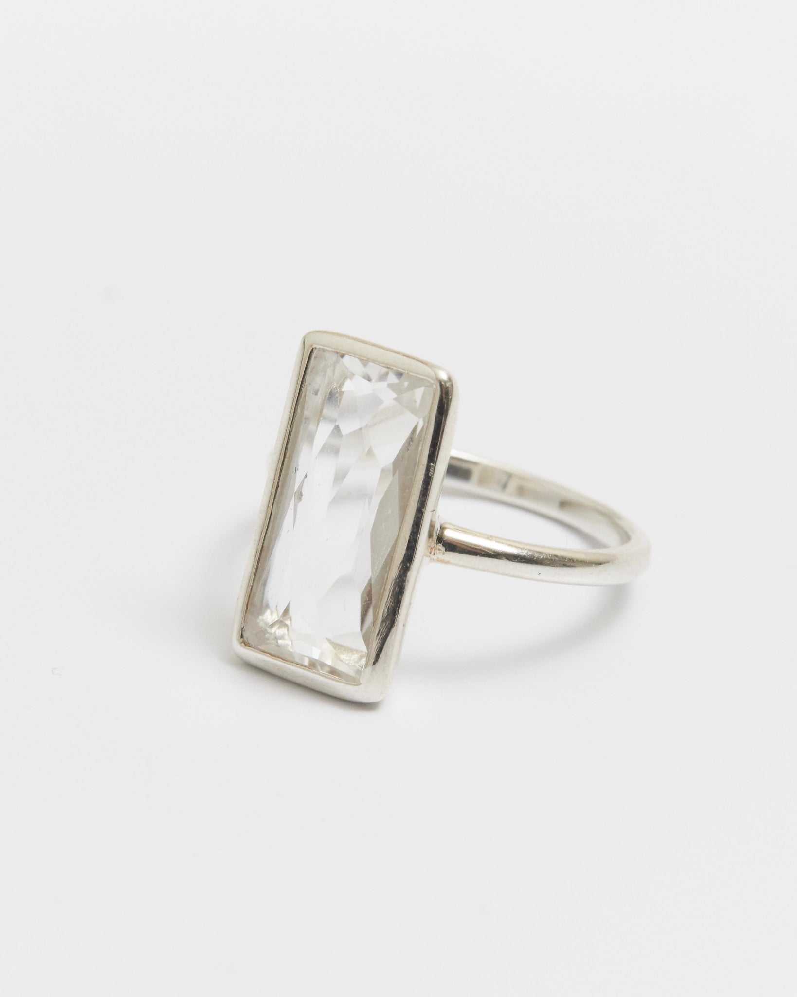 Silver ring with a rectangular gemstone on a light gray background