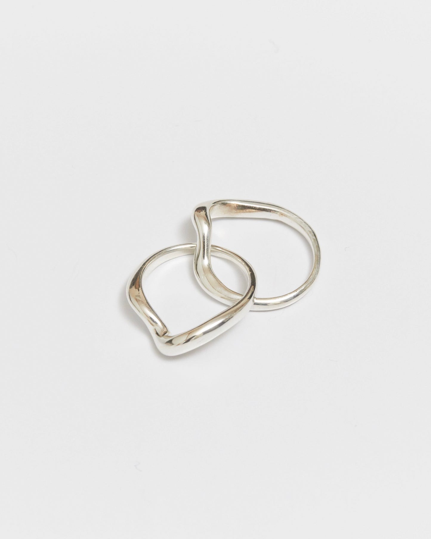 Two interlocking gold rings with softly curved bands on a white background
