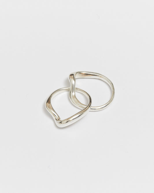 Two interlocking gold rings with softly curved bands on a white background
