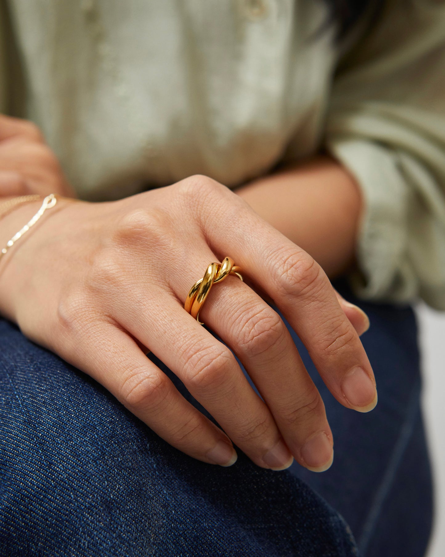 Model with crossed arms wearing a twisted silver ring on ring finger