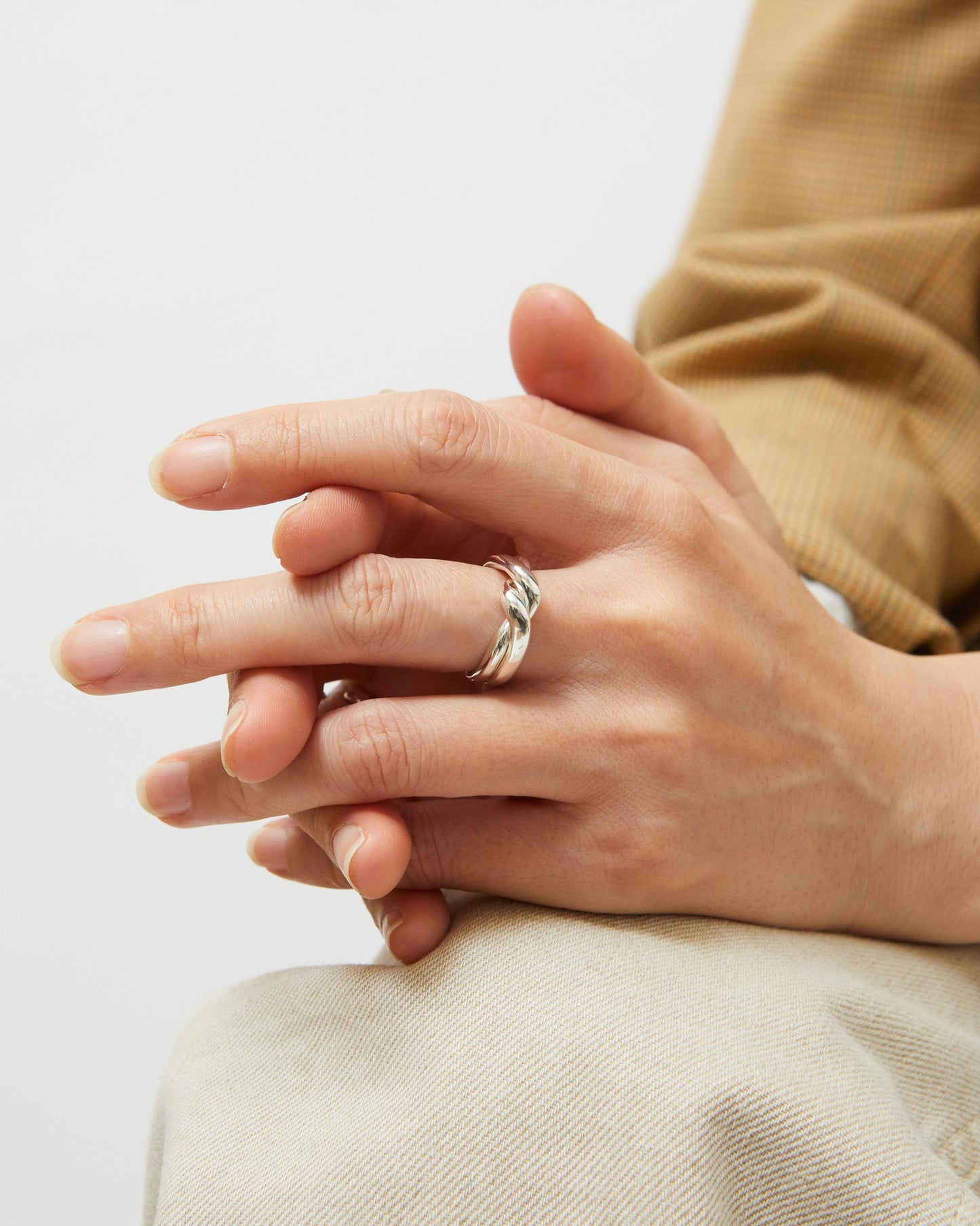 Close-up of a hand wearing a ring on a light background