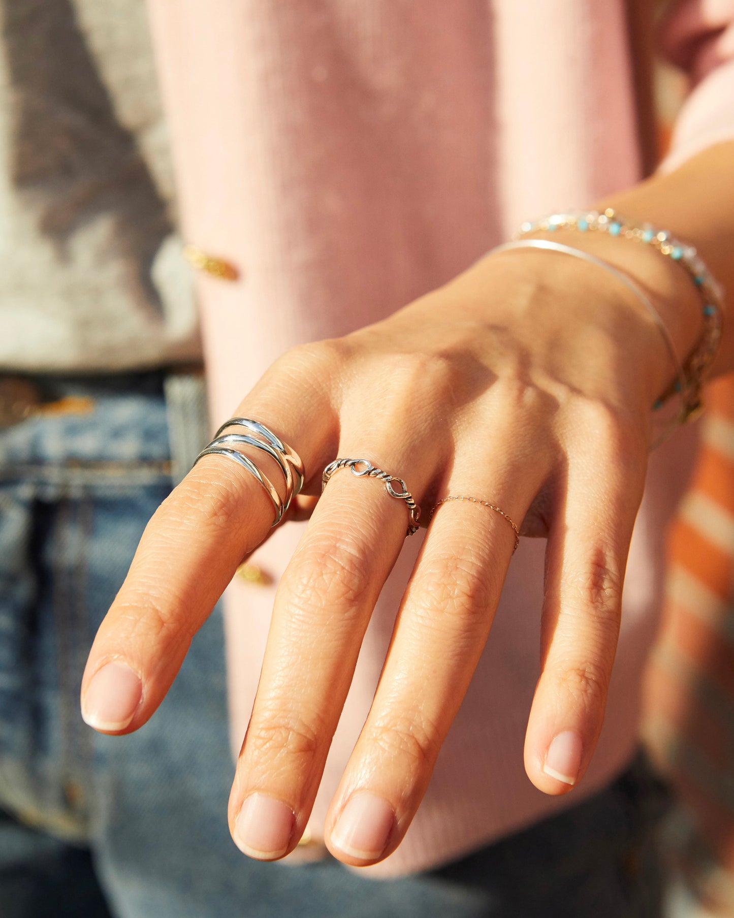 Close-up of a hand with multiple silver rings on a blurred background