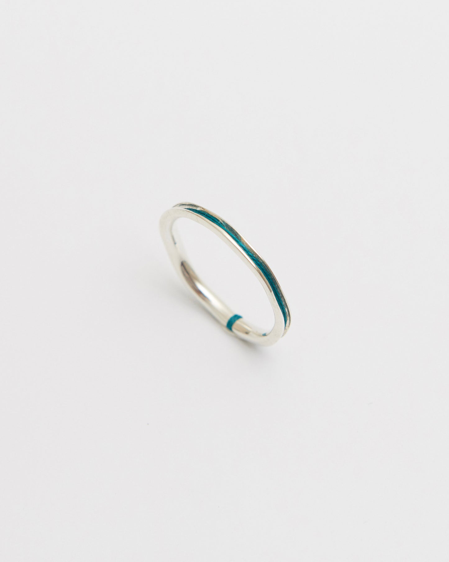 Silver ring with green nylon on a light gray background