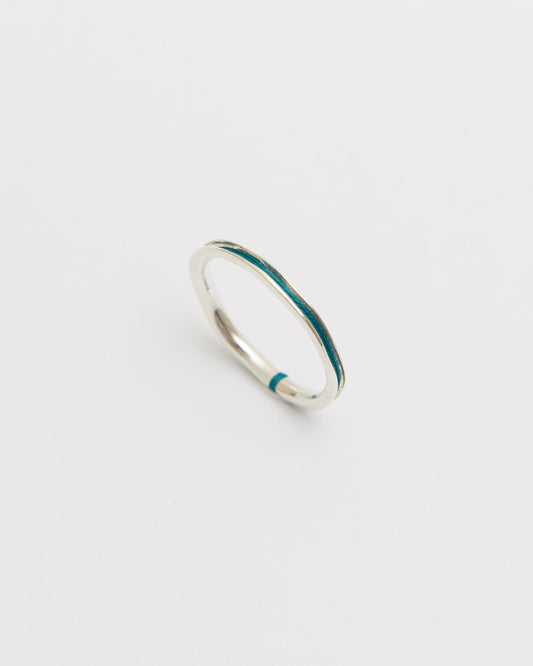 Silver ring with green nylon on a light gray background