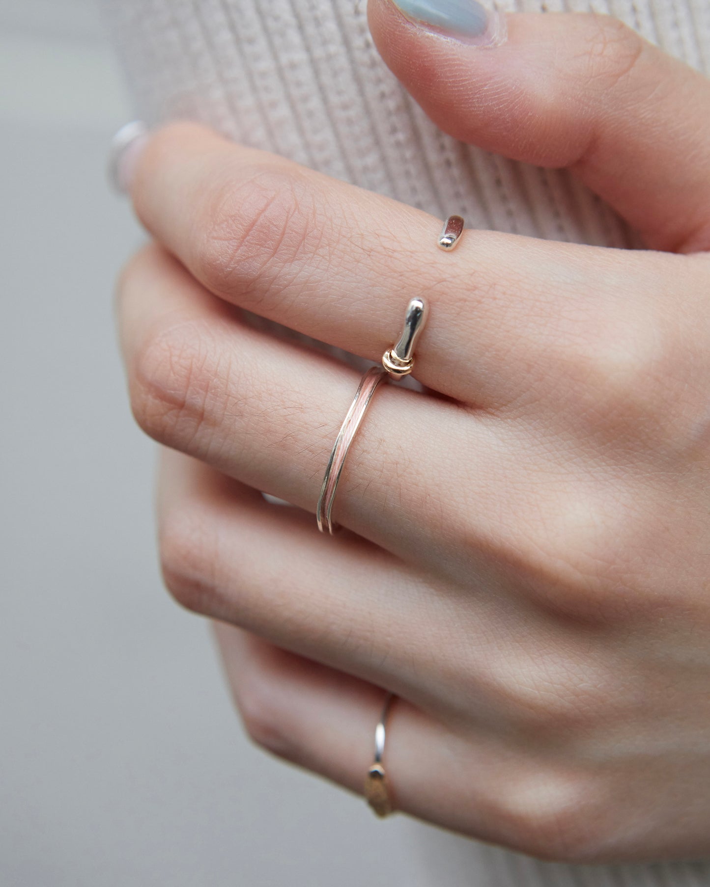 peach minimalist ring styled with a ribbed sweater, worn on the index finger.
