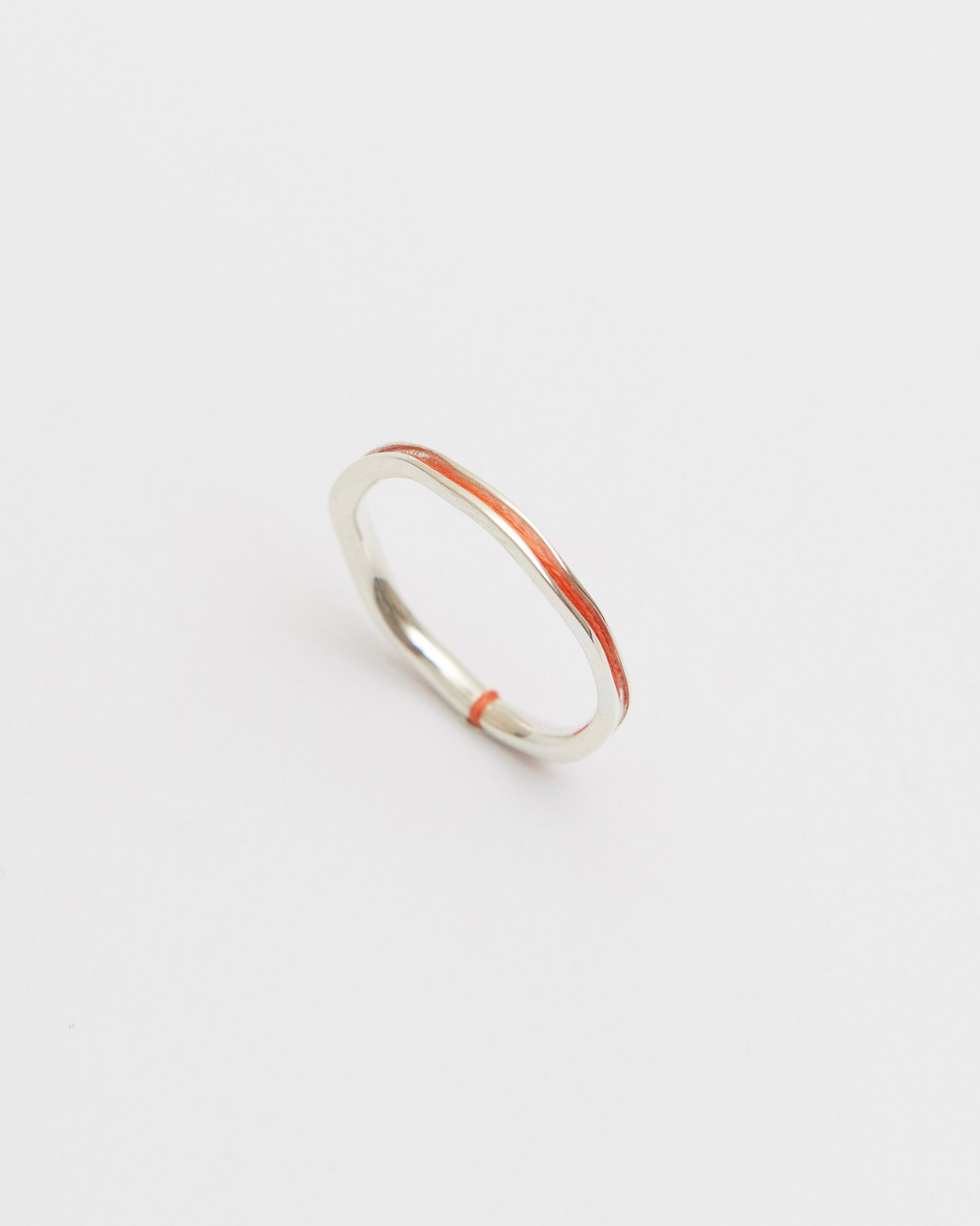 Silver ring with orange accents on a light gray background